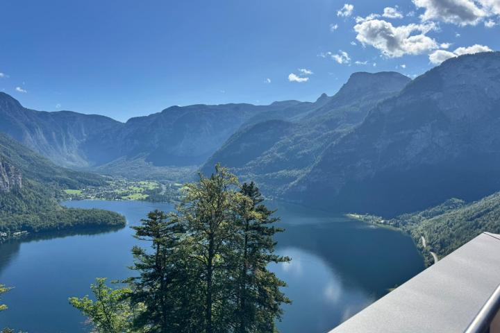 Mountain lake view with trees, under a clear blue sky.