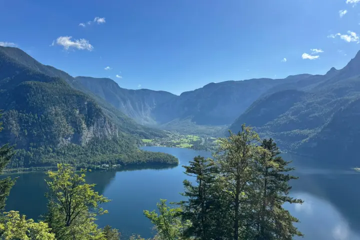 Scenic view of a lake surrounded by mountains and trees under a clear blue sky.