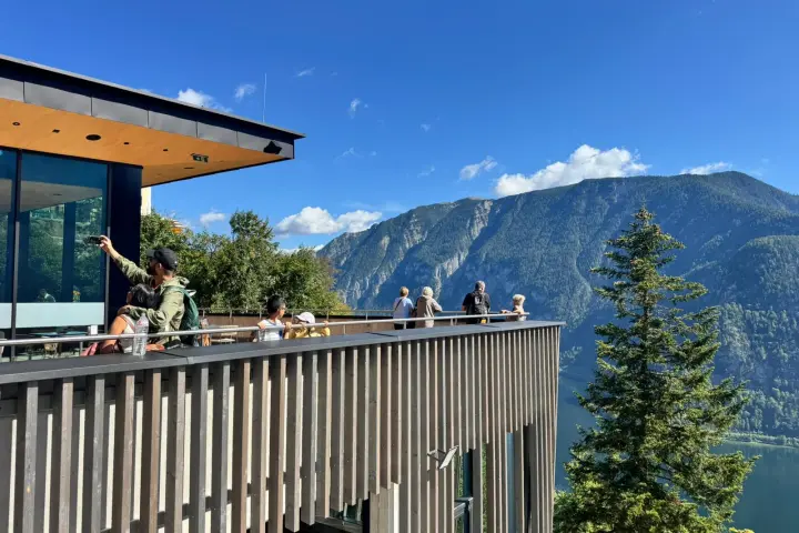 Visitors on a scenic terrace overlooking mountains and a valley.