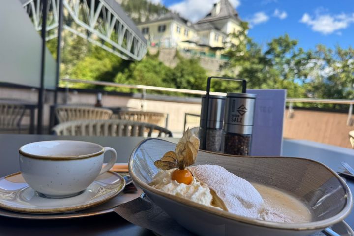 Dessert and coffee on outdoor table with scenic mountain view.