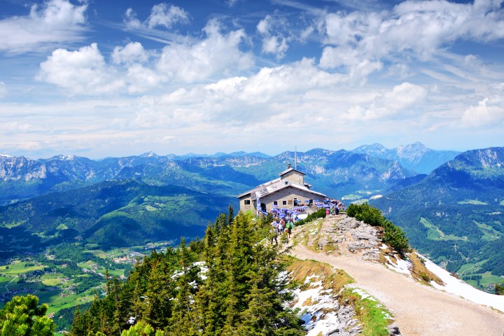 Mountain lodge on peak overlooking scenic valley and distant mountains.