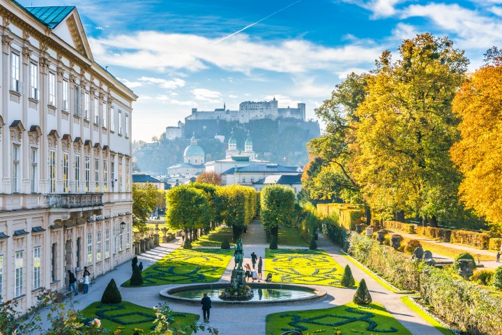 Aerial view of garden and historic building with castle in Salzburg on a sunny day.