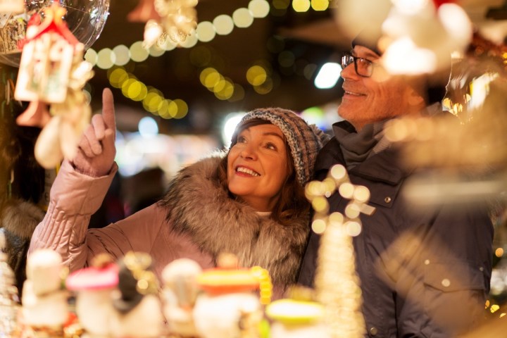 Couple in winter clothing shopping for Christmas decorations at a market.