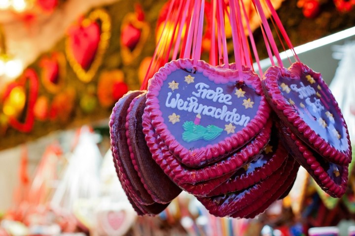 Heart-shaped gingerbread cookies with 'Frohe Weihnachten' hang at a festive market stall.