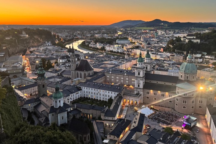 Aerial view of Salzburg at sunset with a river and historic buildings.