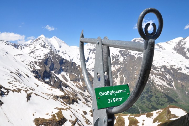 Mountain view with snowy peaks and a Großglockner 3798m sign on metal structure.