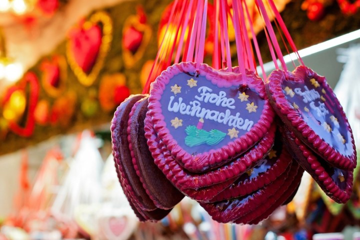 Heart-shaped cookies with 'Frohe Weihnachten' hanging at a festive market.