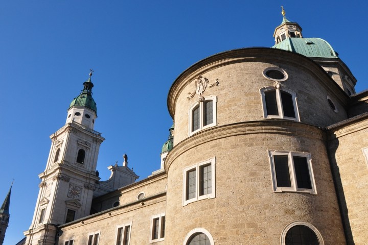 Historic building with tall domed tower against a clear blue sky.