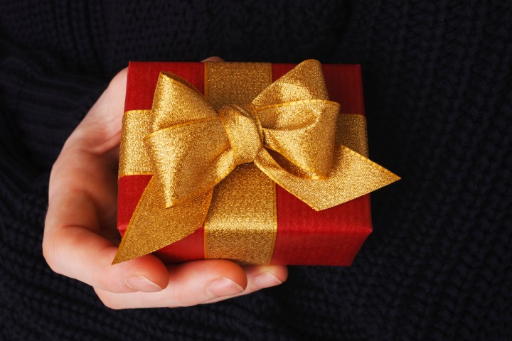 Hand holding a small red gift box with a gold bow.
