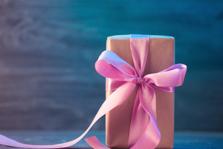 Gift wrapped in brown paper with a pink ribbon bow against a blue background.
