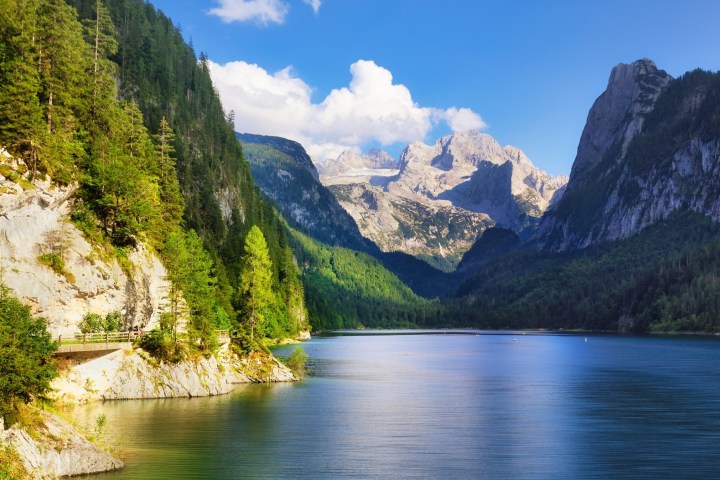 Alpine lake with surrounding forested mountains under a clear blue sky.