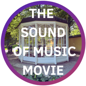 White gazebo with 'The Sound of Music Movie' text, surrounded by trees.