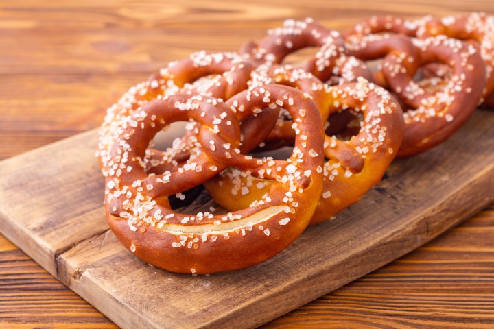 Salted pretzels on a wooden board with a wooden table background.