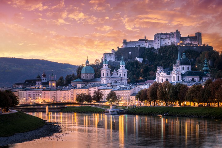 Scenic view of Salzburg with a castle on a hill at sunset.