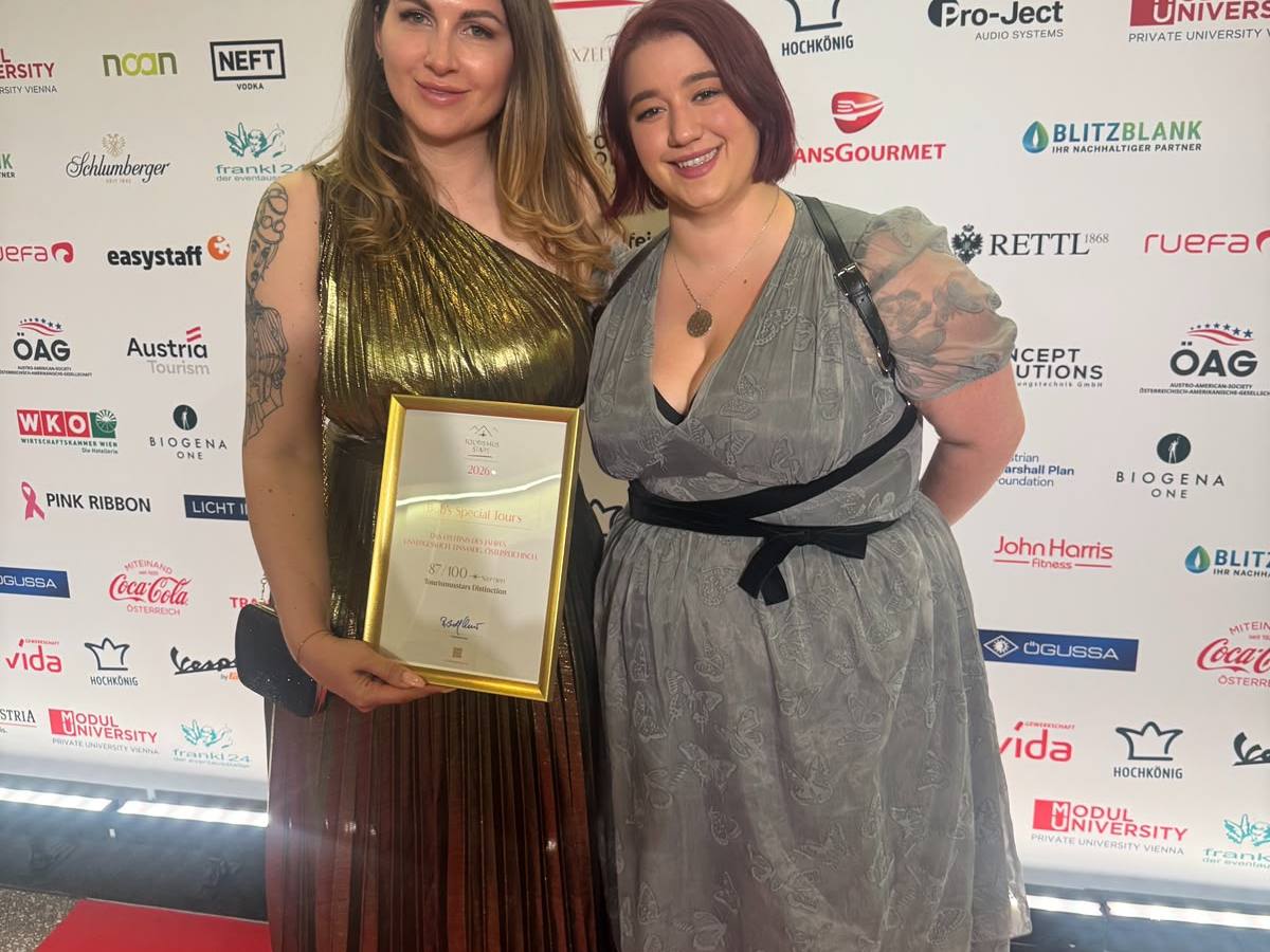 Two women posing with an award on a red carpet at a tourism event.
